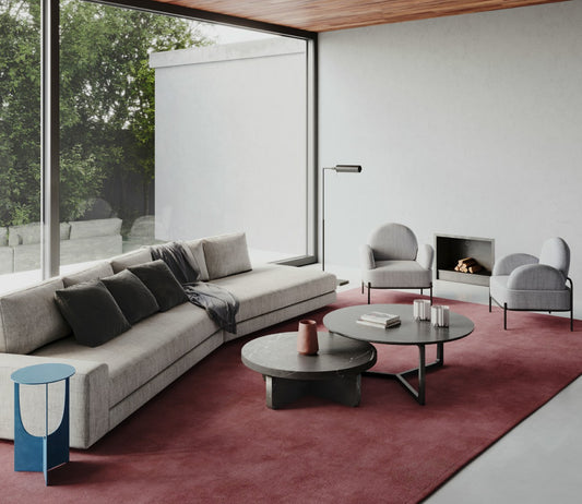 Modern living room with gray sofa, burgundy carpet, round coffee tables and floor-to-ceiling windows
