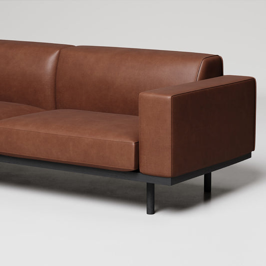 Modern brown leather sofa with clean lines, black metal legs, and minimal design against light gray background