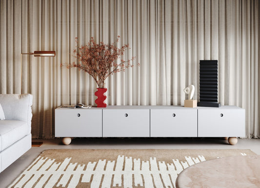 Modern living room with white credenza, red vase with dried flowers, geometric rug, and minimalist decor against curtains