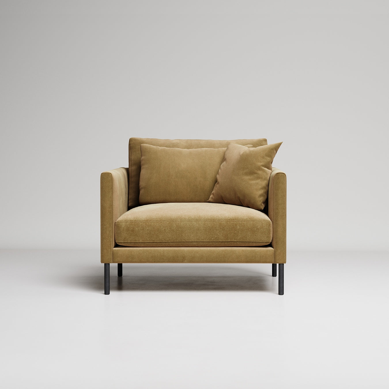 Modern tan velvet armchair with black metal legs, two matching throw pillows, against light gray background