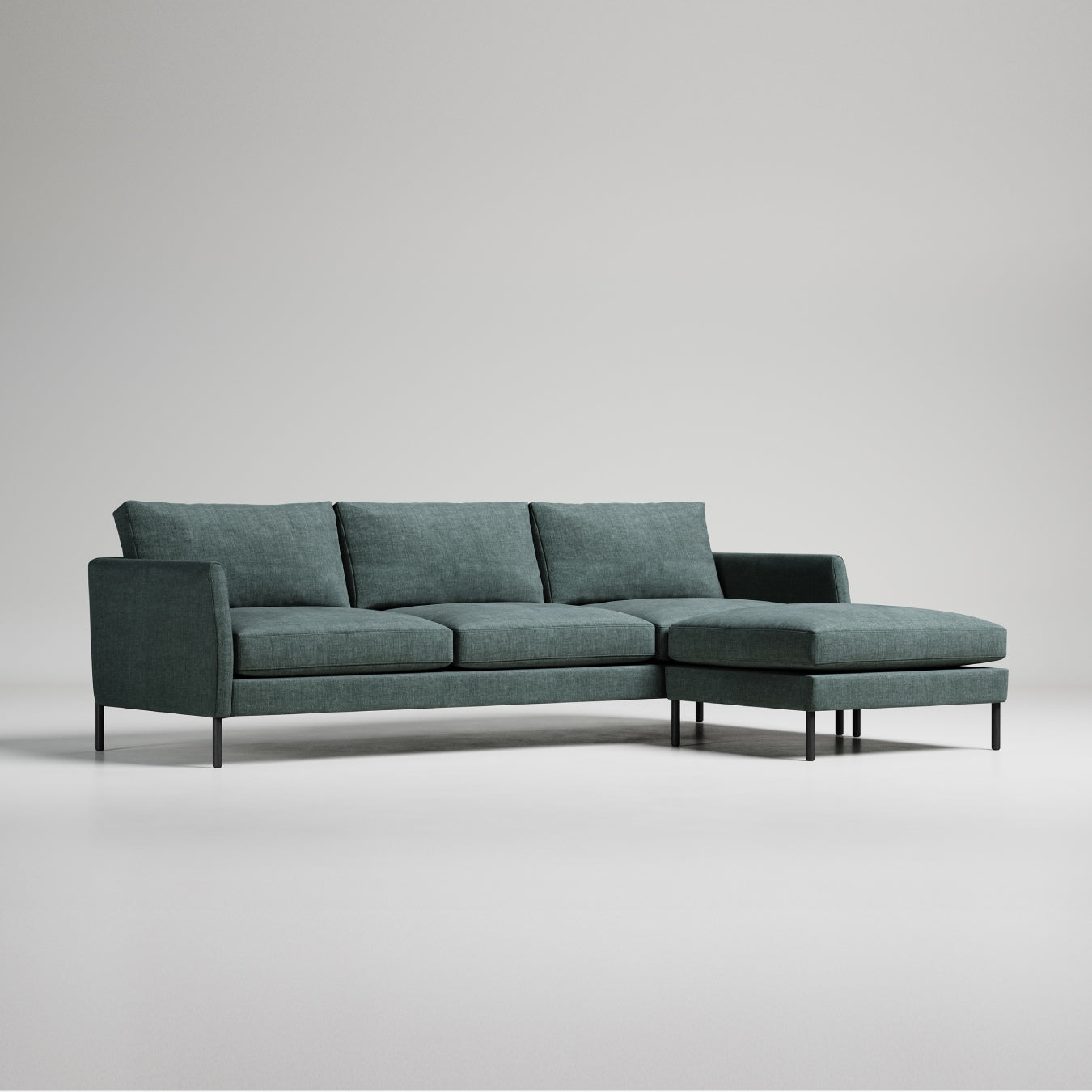 Modern green sectional sofa with chaise lounge, black metal legs, against white background, minimalist design