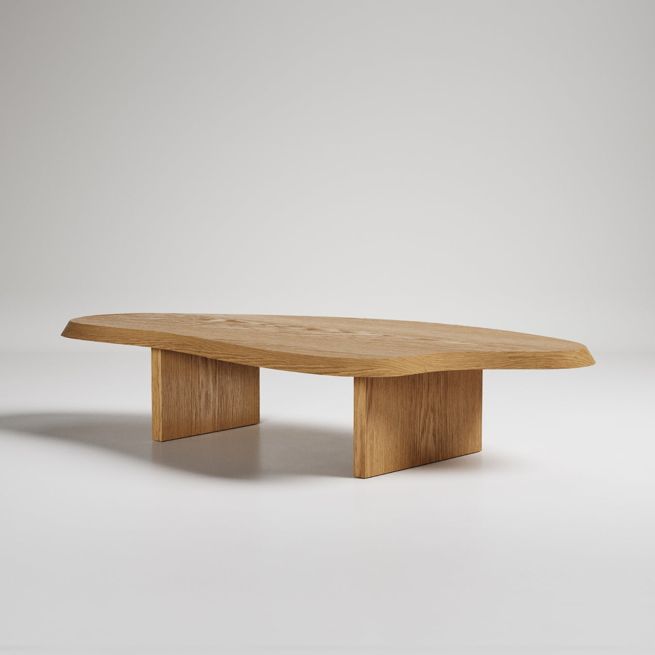 Modern oak coffee table with organic surfboard shape and two rectangular pedestal legs on white background