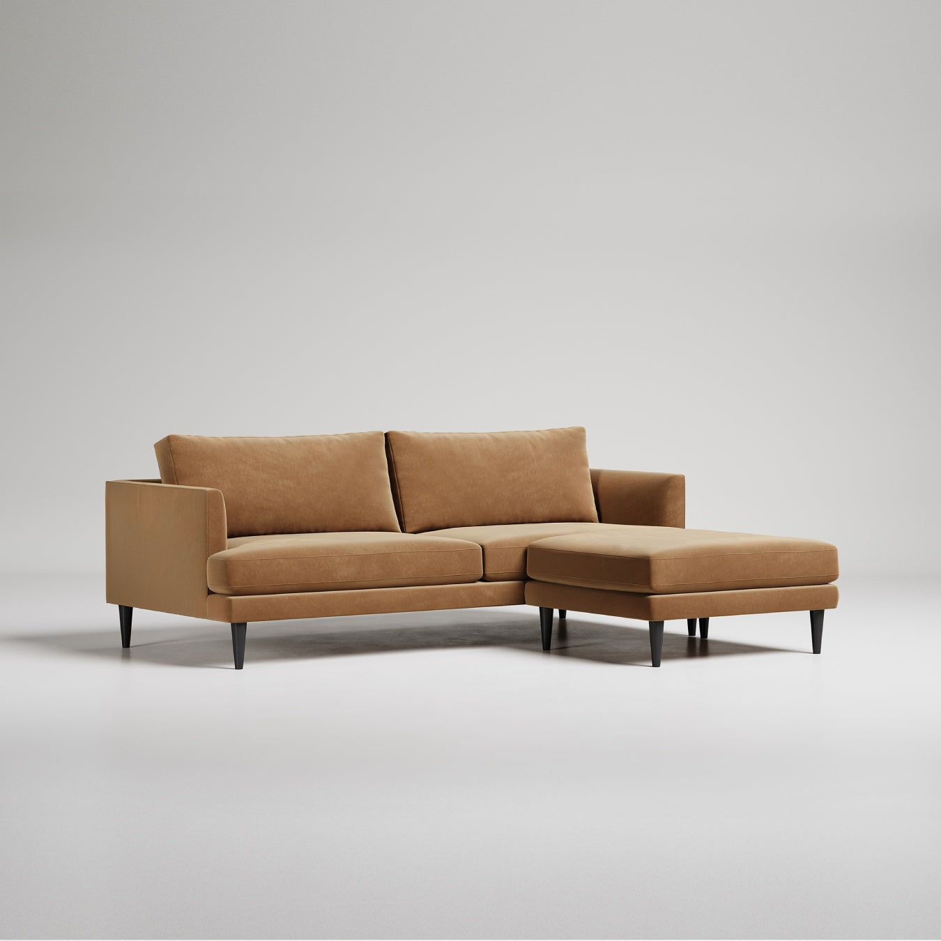 Modern tan leather sectional sofa with chaise lounge on black legs, shown against light gray backdrop