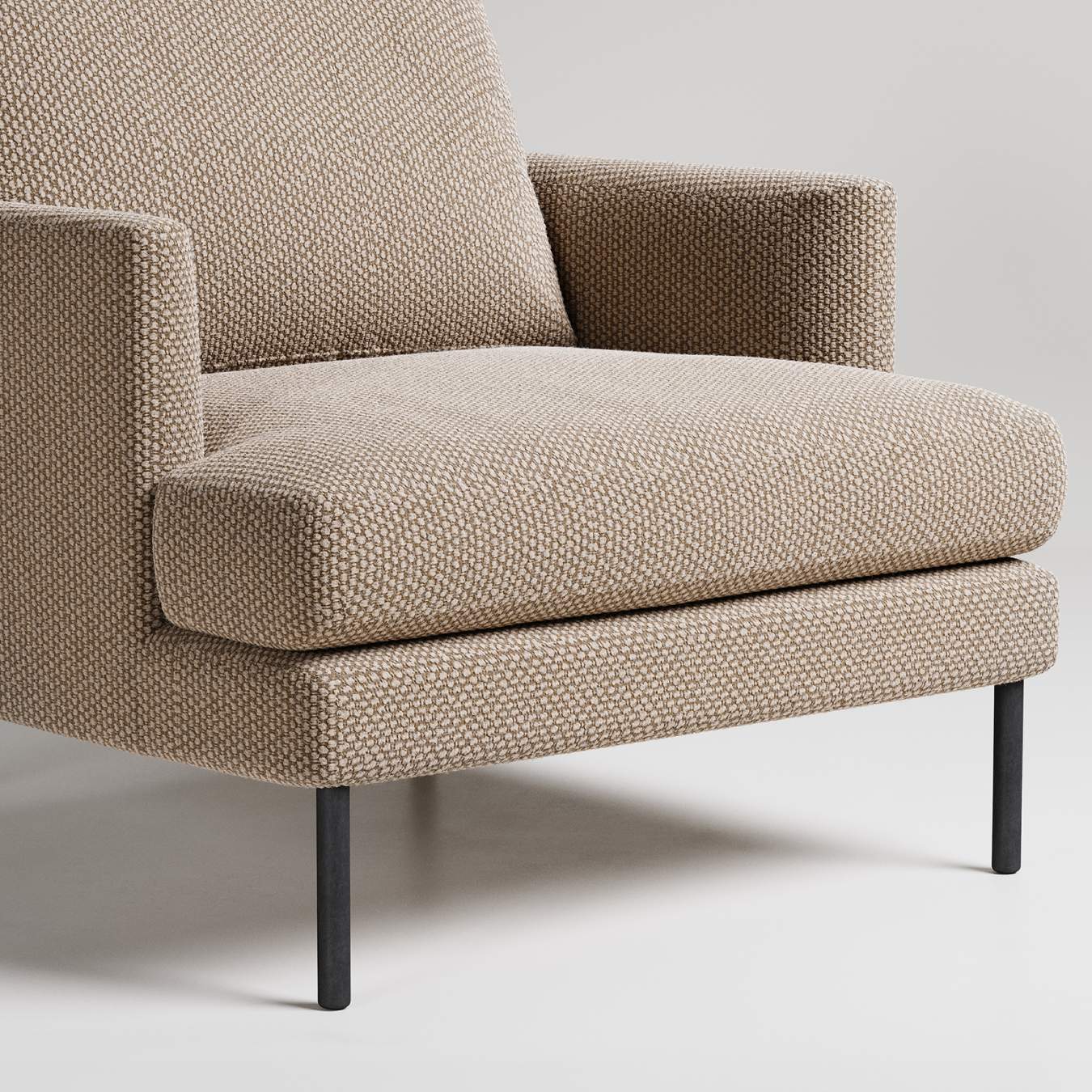 Modern armchair with textured beige upholstery and black metal legs, shown in close-up detail against white background