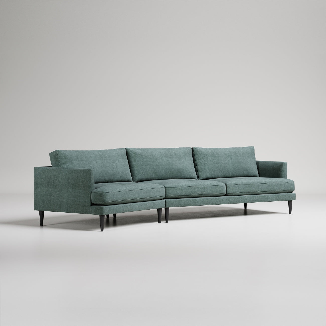 Modern sage green sectional sofa with clean lines, tapered legs, and loose back cushions on light gray background