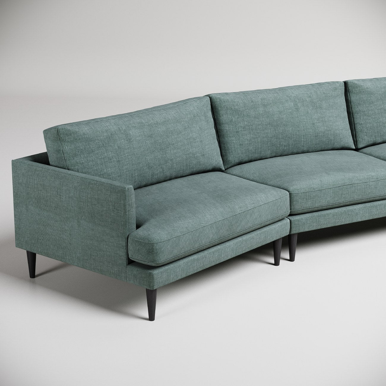 Mid-century modern curved sectional sofa in sage green fabric with tapered black legs, photographed on white background