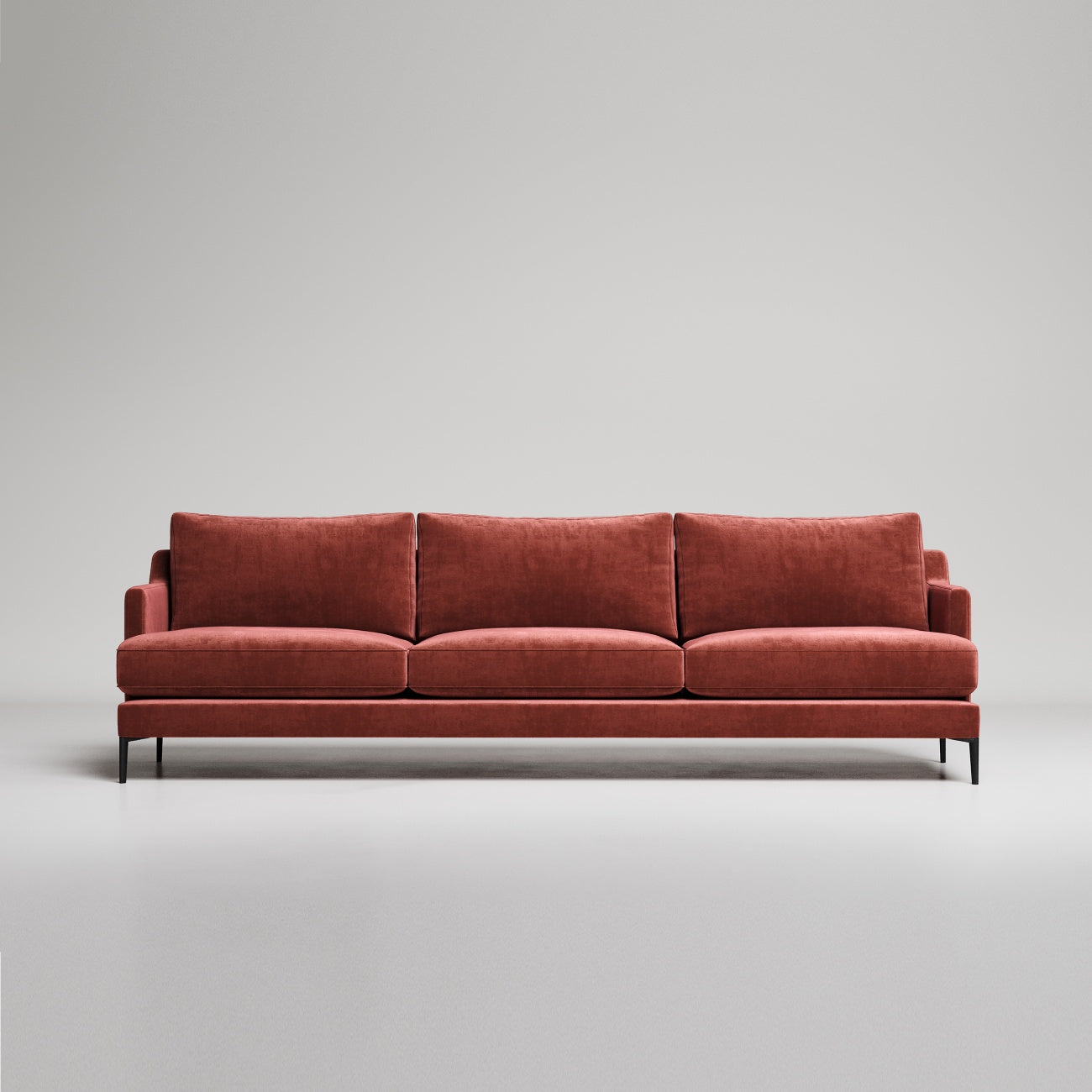 Modern three-seater sofa in rust velvet upholstery with black metal legs against light gray background