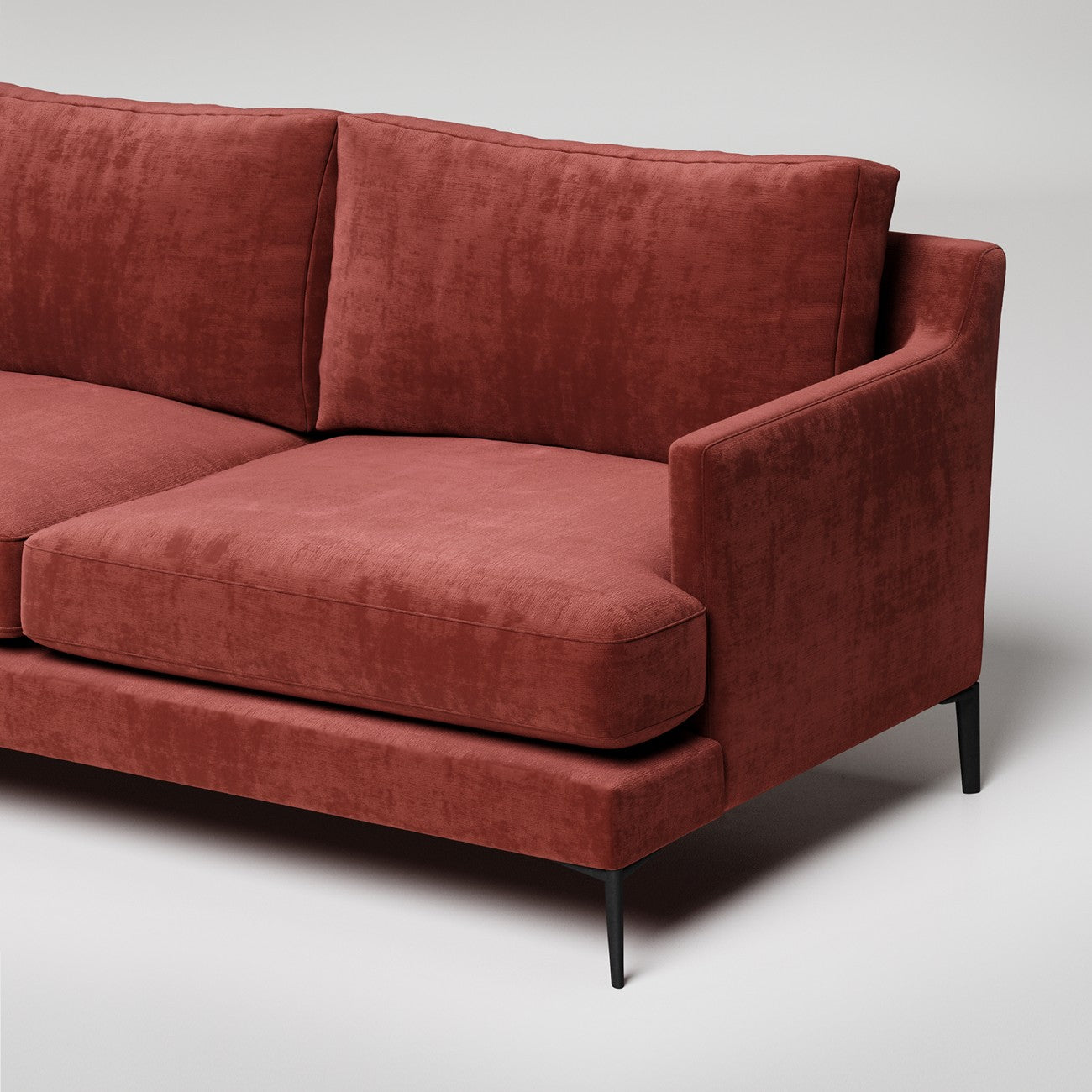 Modern terracotta velvet sofa with black metal legs, shown in close-up against white background