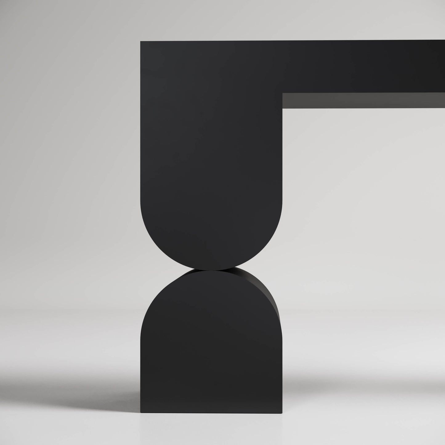 Modern minimalist black vase or sculpture with U-shaped top balanced on curved base against light background