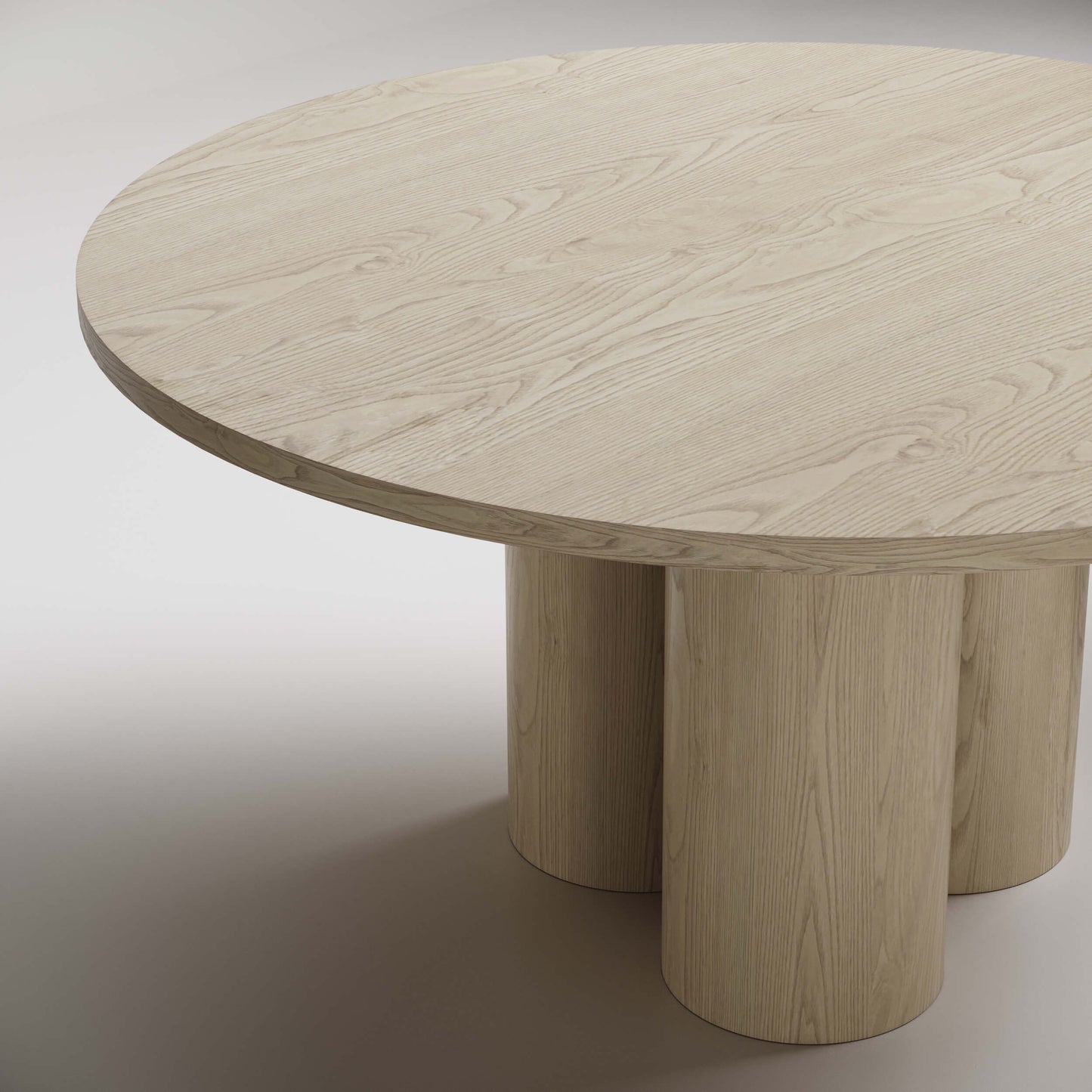 Modern round dining table with light wood finish and three cylindrical pedestal legs, shown against white background