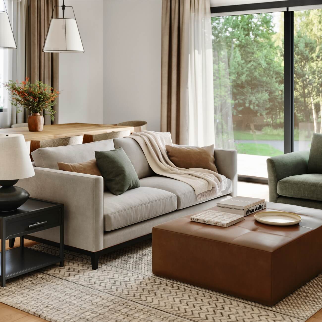 Modern living room with beige sofa, leather ottoman, green accents, natural light, dining area and geometric rug
