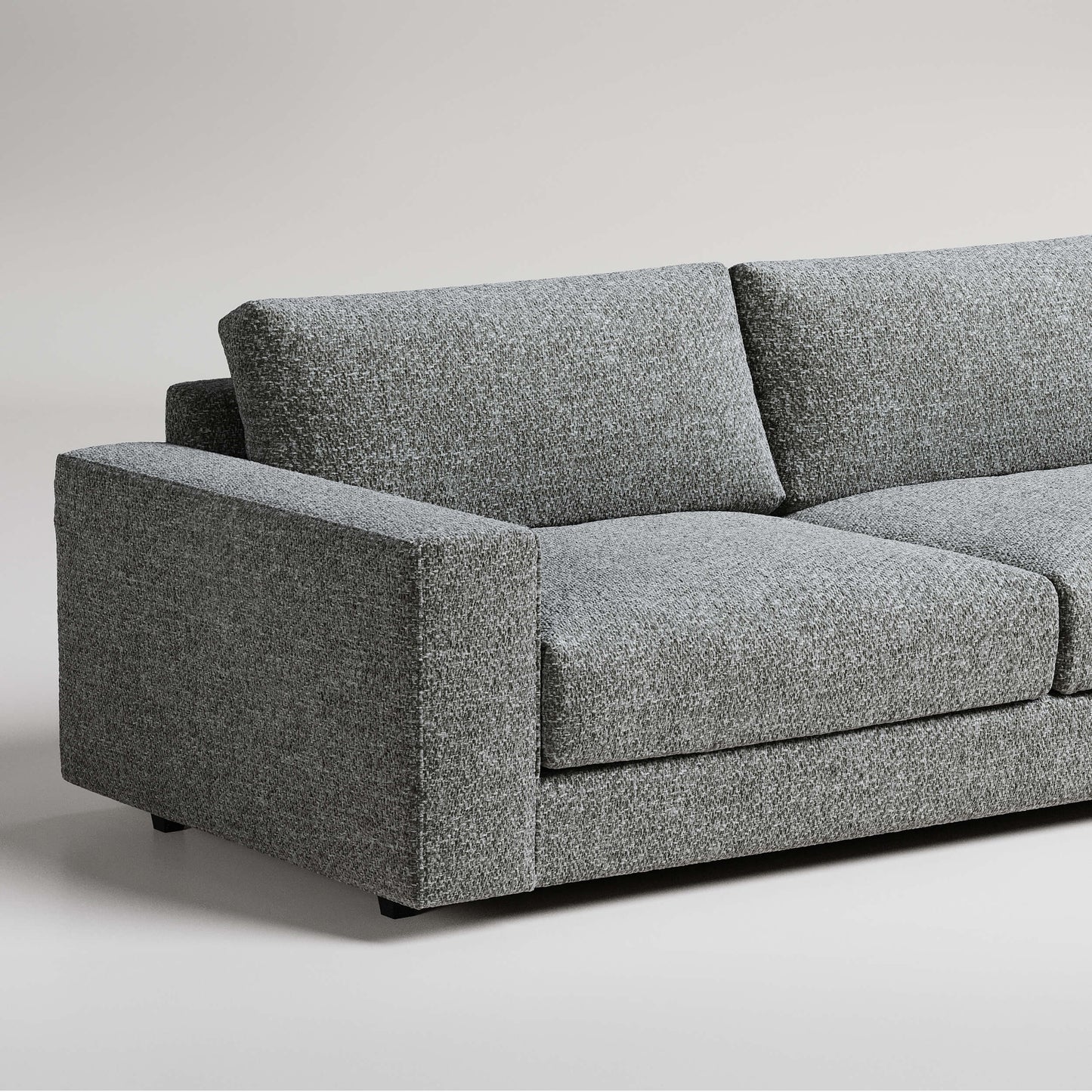 Modern grey tweed sofa with clean lines and square arms photographed against light background