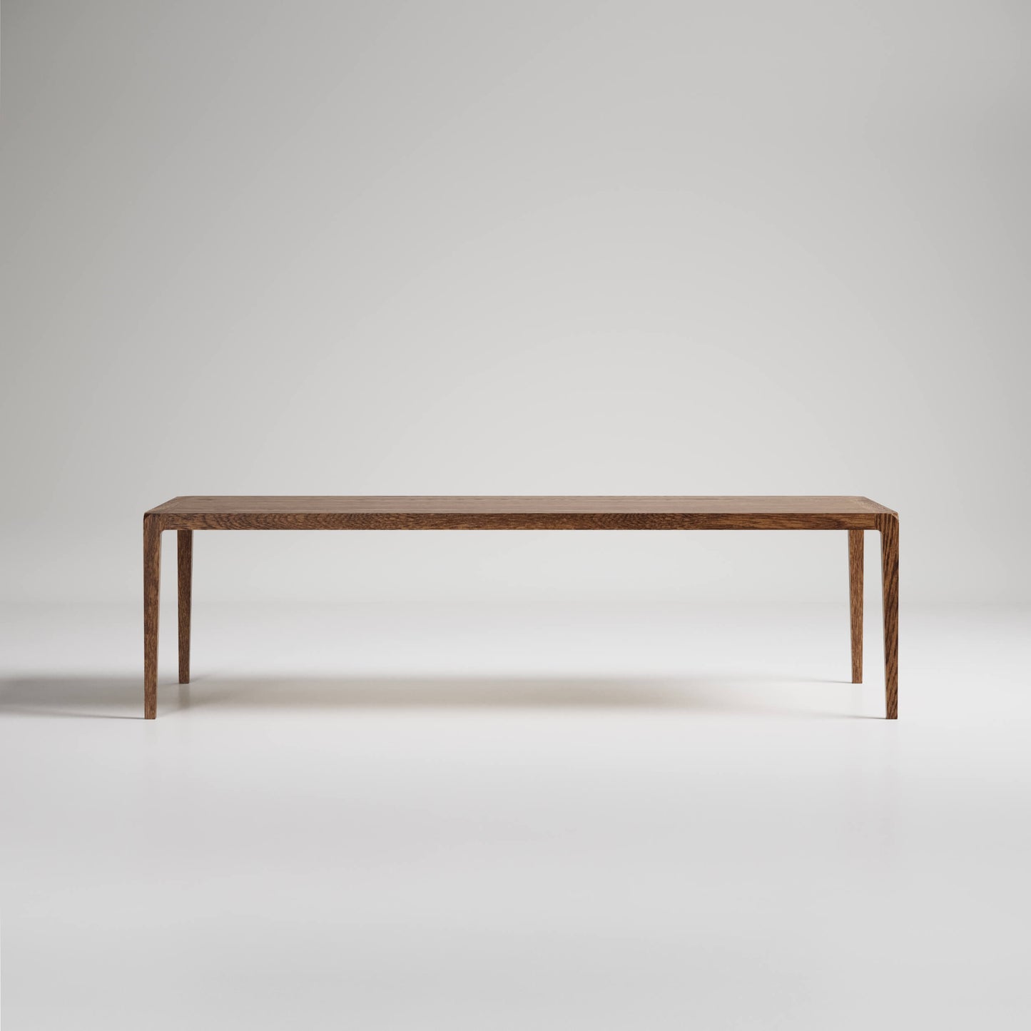 Minimalist wooden dining table with slim tapered legs against white background, showcasing clean modern design