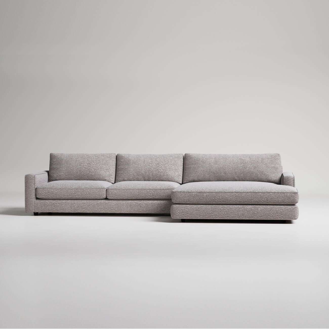 Modern gray L-shaped sectional sofa with textured fabric upholstery on white background, minimalist design