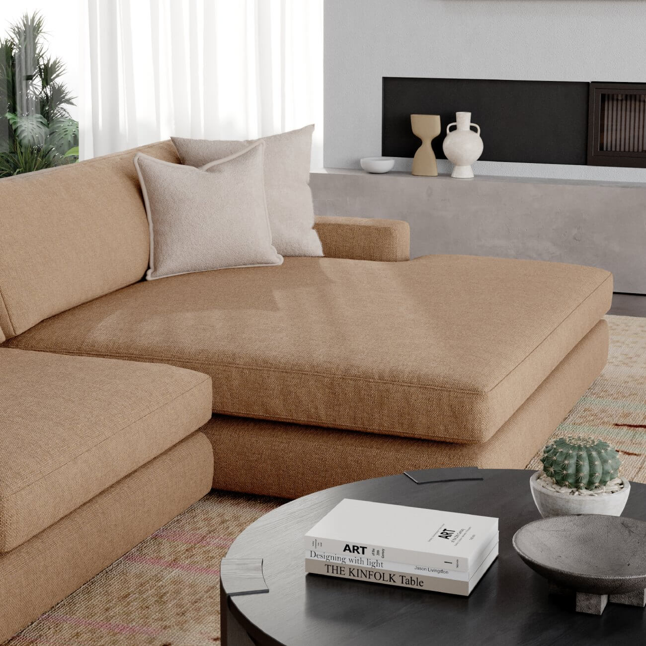 Modern beige sectional sofa with throw pillows, round coffee table, art books and minimal decor in neutral living room