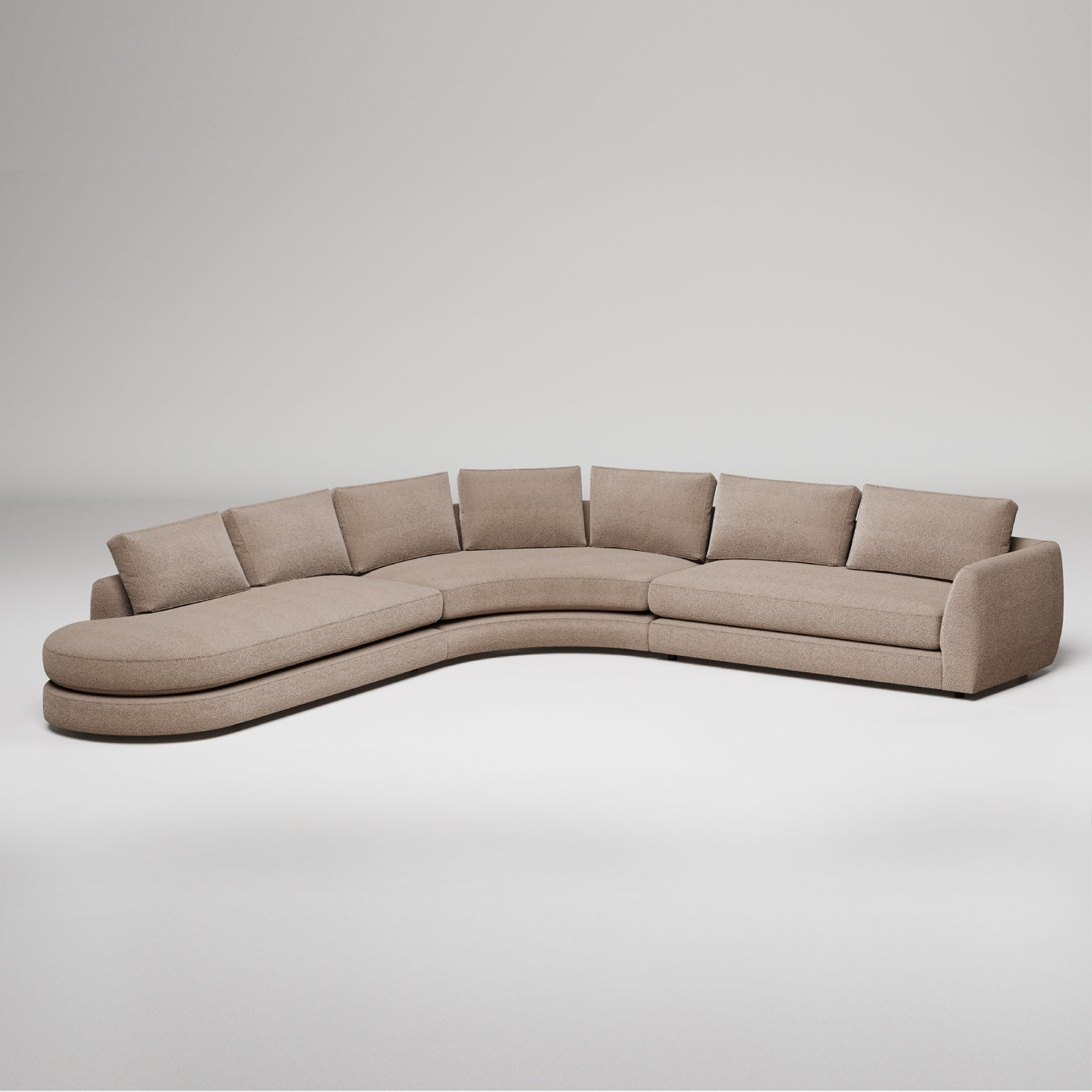 Modern curved sectional sofa in camel textured fabric with curved chaise lounge and cushions against gray background