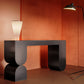 Black sculptural console table in front of a burnt orange wall