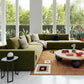 Large green modular sofa and coffee table in a living room with floor to ceiling windows